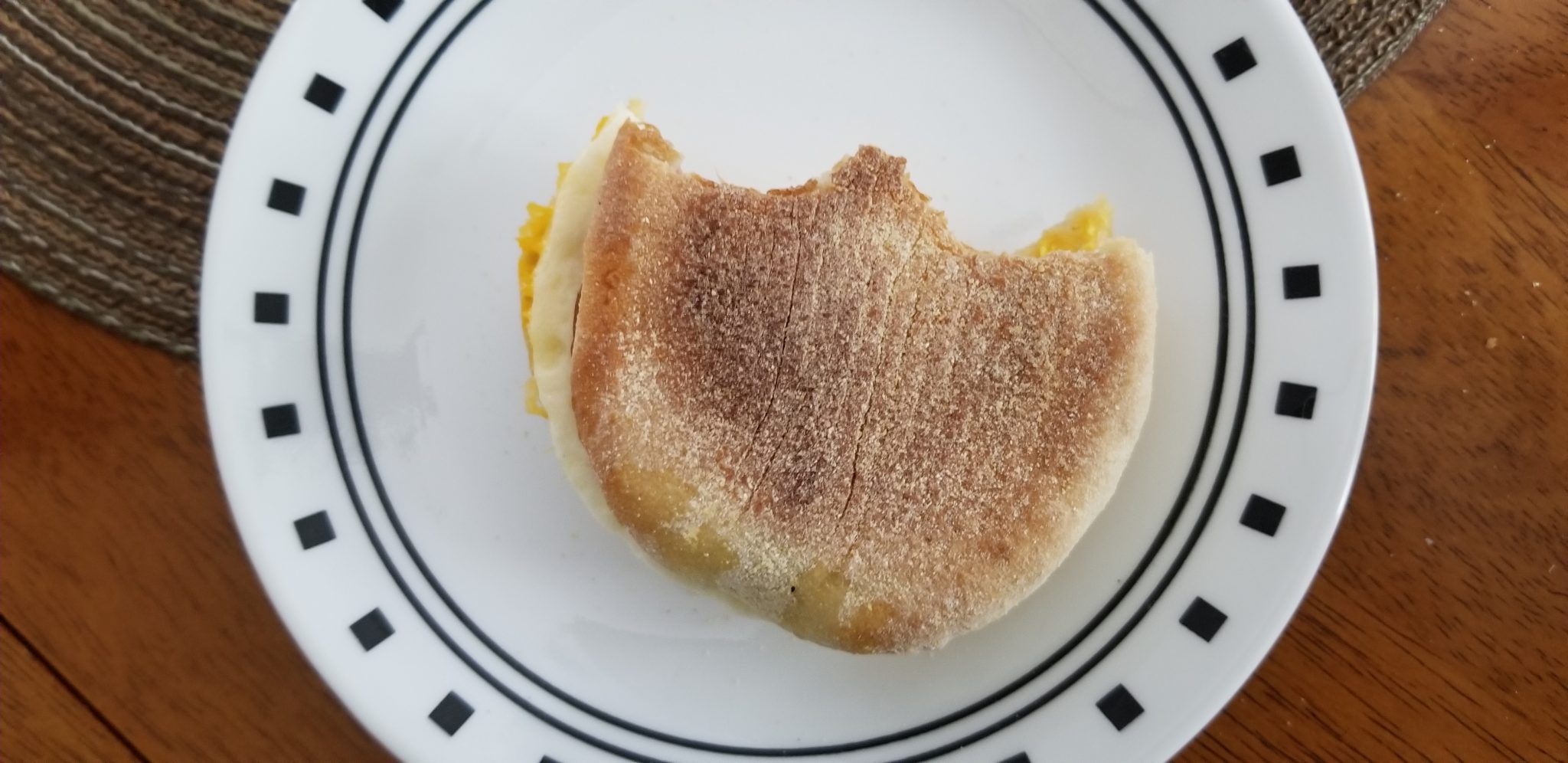 Jimmy Dean English Muffin, Canadian Bacon, Whole Egg and Cheese with two bites up close.