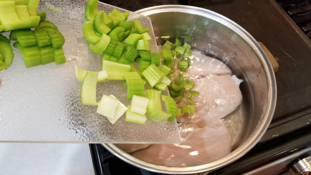 putting celery into the pot for chicken salad recipe