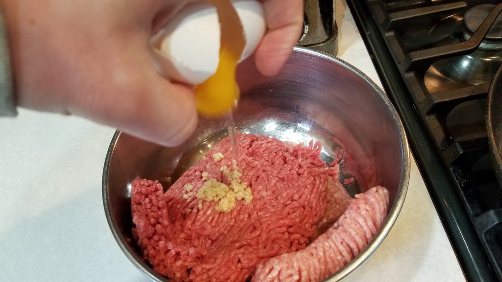 cracking an egg for meatball recipe
