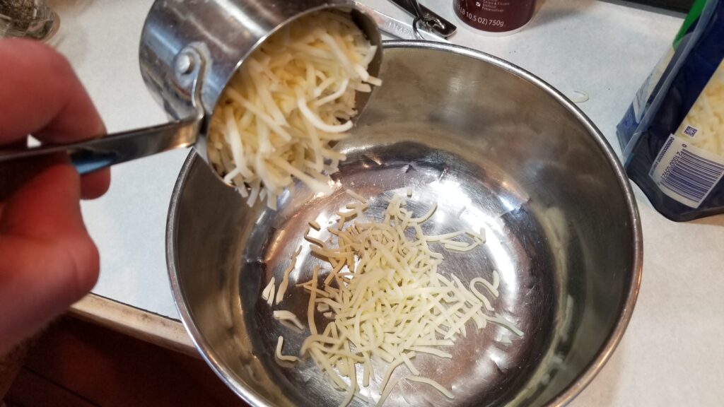 dumping mozzarella into bowl for manicotti recipe