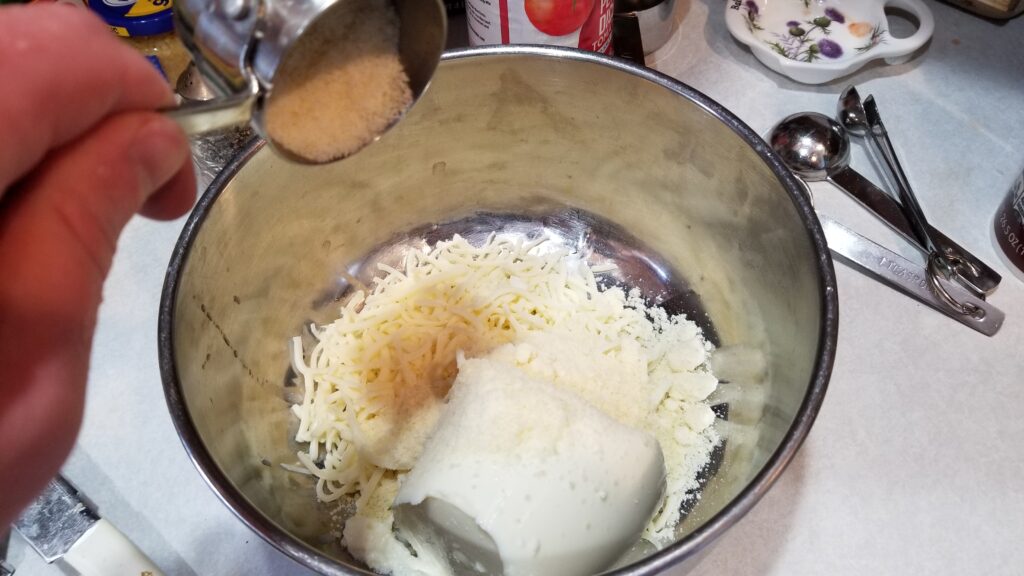 dumping parmesan into bowl with other cheese for manicotti recipe.