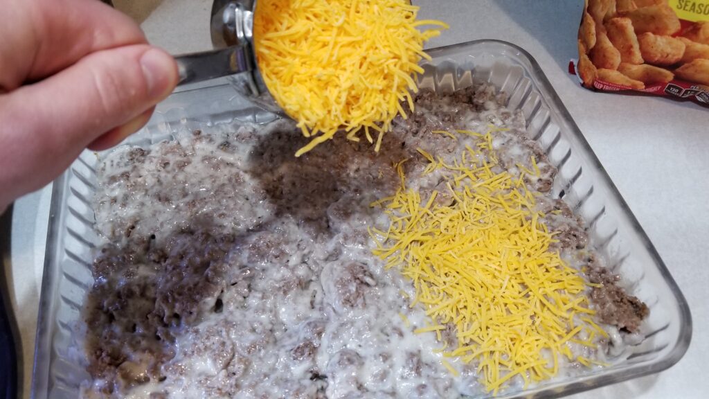 dumping cheese into tater tot casserole
