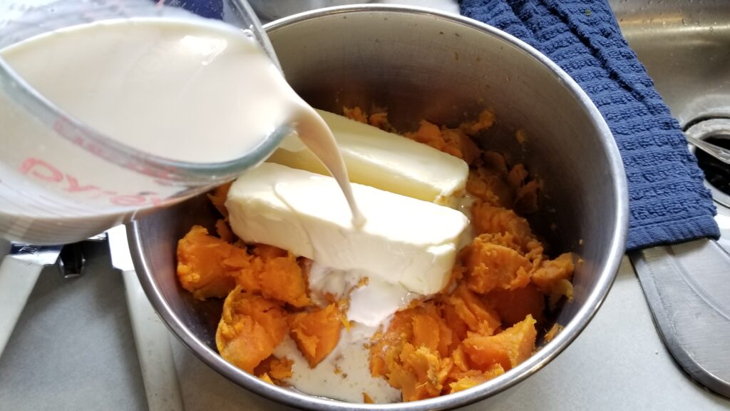 pouring evaporated milk into sweet potato pie ingredients