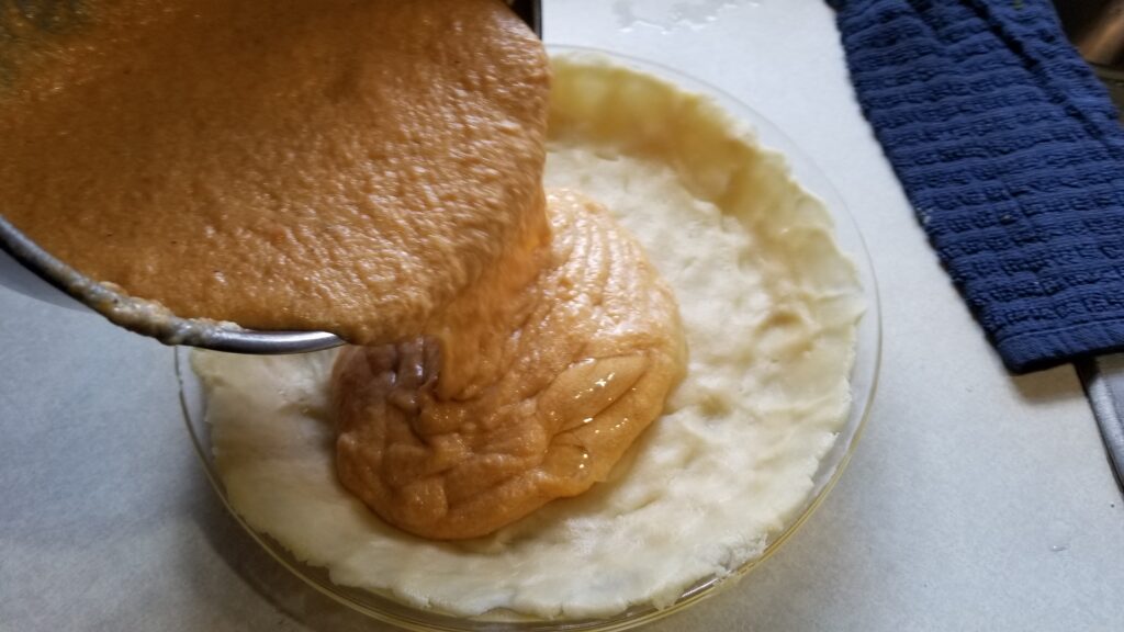 pouring sweet potato pie mixture into pie plate