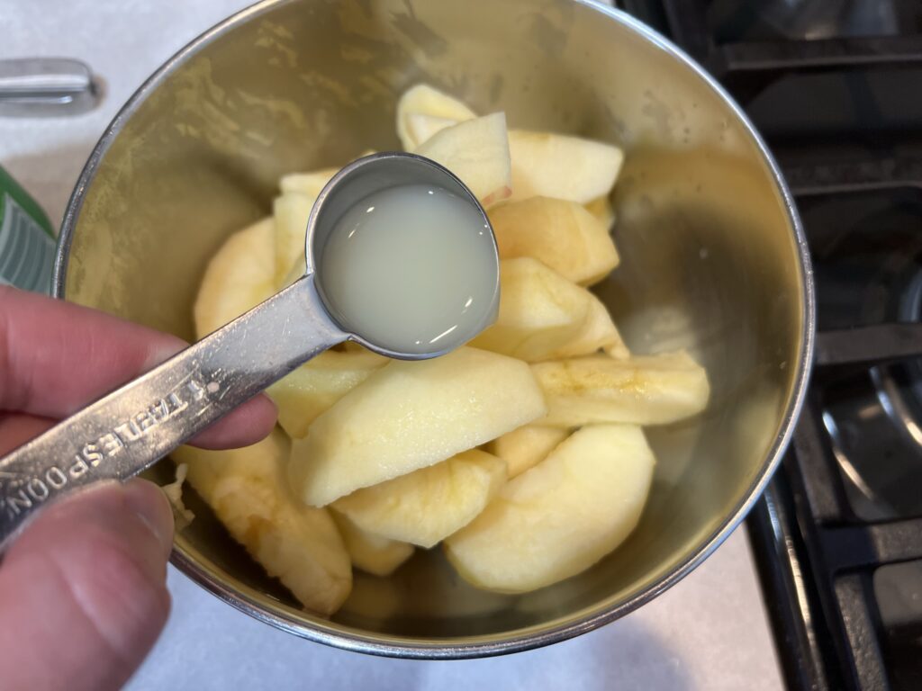 dumping lemon juice on apples for apple pie recipe