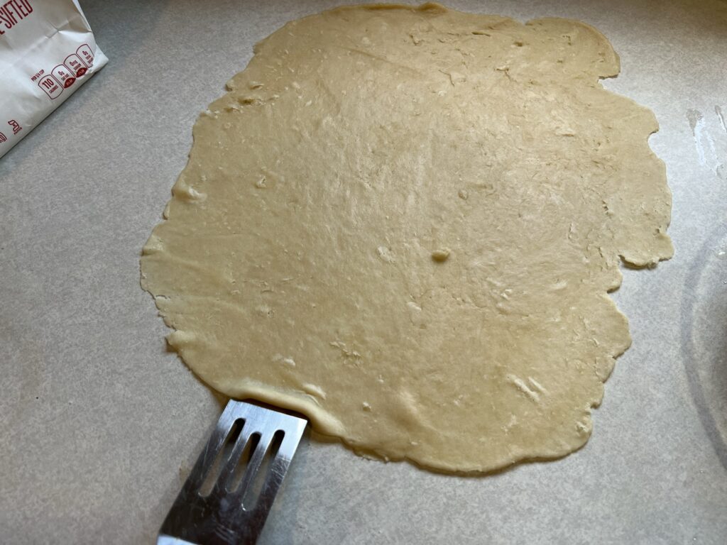 spatula scraping pie crust dough off counter