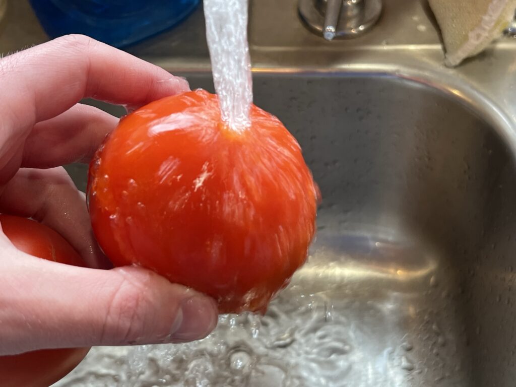 washing a tomato for gemelli pasta salad