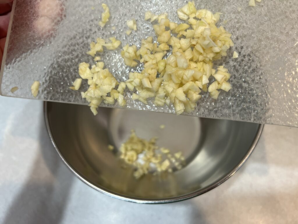 scraping garlic into a large bowl for Tagliolini
